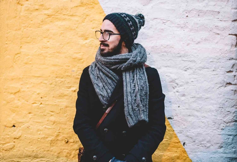 Mann steht vor einer Wand in Winterkleidung